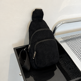 Black corduroy sling bag with adjustable woven strap and zip pockets
