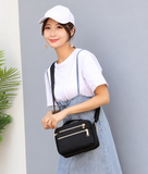 Model wearing the black compact crossbody bag