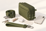 Olive green wallet with detachable straps and everyday essentials shown alongside